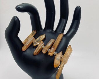 May include: A bracelet made of multiple golden brown crystal points with clear crystal beads in between.