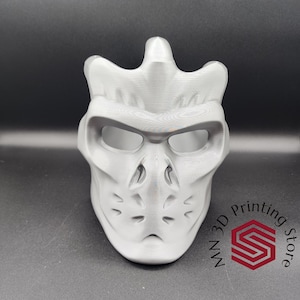 May include: A white 3D printed mask with a skull-like design. The mask has eye holes and a detailed, textured surface.