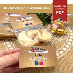May include: A close-up of a Christmas-themed gift set. The set includes cookies, candies, and a card with the text "Frohe Weihnachten." The image also features the text "DIGITALER DOWNLOAD PDF."
