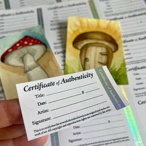Op de afbeelding: Een verzameling aquarelprints met paddenstoelillustraties, vergezeld van meerdere "Certificaat van Echtheid" kaarten. De kaarten hebben velden voor titel, datum, kunstenaar en handtekening, met copyrighttekst.