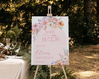 May include: A pink and white floral baby shower welcome sign with the text "Baby in Bloom" and "Olivia's Baby Shower" with the date August 21, 2024.