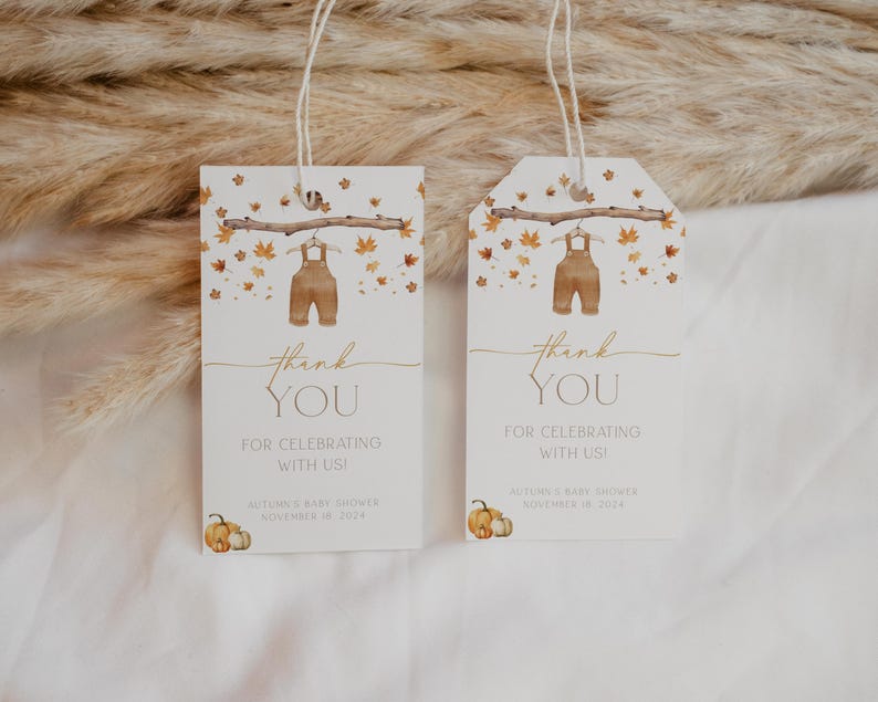 May include: Two white baby shower thank you tags. Each tag features a watercolor illustration of brown overalls hanging from a branch with autumn leaves. The text reads "thank YOU FOR CELEBRATING WITH US!" and includes the baby shower date.