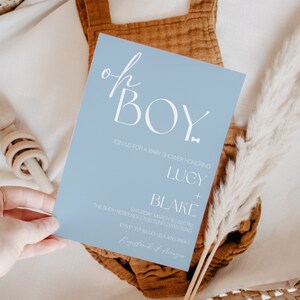 May include: A light blue baby shower invitation with white text that reads "Oh Boy" in a script font. The invitation includes details for the event, including the date, time, and location.