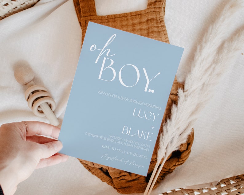 May include: A light blue baby shower invitation with white text that reads "Oh Boy" in a script font. The invitation includes details for the event, including the date, time, and location.