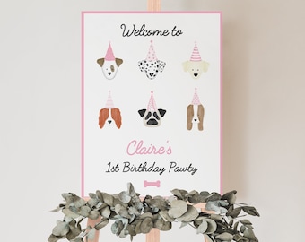 May include: A pink and white welcome sign with the text "Welcome to Claire's 1st Birthday Pawty" and illustrations of dogs wearing pink party hats.