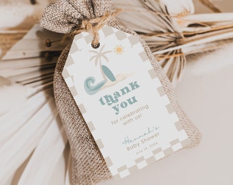Op de afbeelding: Een klein jute zakje vastgebonden met touw, met een label met een strandthema. Het label bevat een palmboom, surfboard en de woorden "thank you" in blauw, samen met de tekst "Hannah's Baby Shower July 13, 2024".