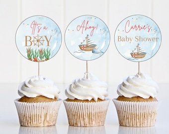 Puede incluir: Tres cupcakes decorados con toppers de cupcakes de temática náutica azul y blanca. Los toppers representan un barco, un volante y el texto "It's a Boy", "Ahoy!" y "Carrie's Baby Shower".