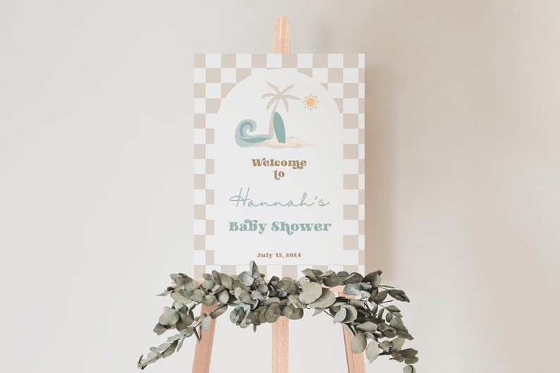 May include: A welcome sign for a baby shower with a beach theme. The sign has a checkered background and a graphic of a palm tree, surfboard, and wave. The text reads "Welcome to Hannah's Baby Shower July 13, 2024".