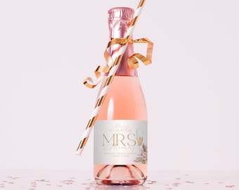 May include: A small bottle of pink champagne with a white and gold striped straw and gold ribbon. The bottle has a white label with gold text that reads "Cheers to the future Mrs. Thomas" and "Madison's Bridal Shower March 12, 2023".