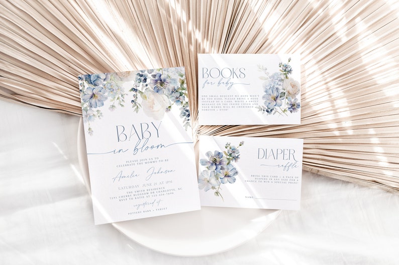 May include: Blue and white floral baby shower invitation cards with the text "Baby in Bloom" and "Books for Baby" and "Diaper Raffle".