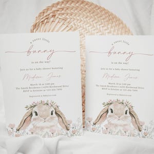 May include: A baby shower invitation with a pink and white floral design featuring a cute bunny rabbit with a flower crown. The text reads "A sweet little bunny is on the way!" and includes the name "Madison Jones" and details for the shower.