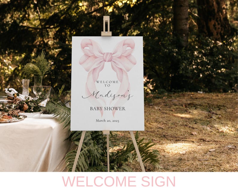 May include: Welcome sign for a baby shower with a pink watercolor bow and the text "Welcome to Madison's Baby Shower March 20, 2023".