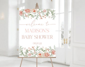 May include: A white welcome sign with pink floral borders. The text reads "Welcome to Madison's Baby Shower 08.20.22".