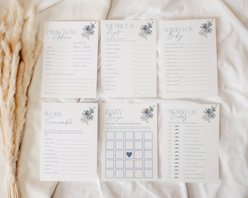 May include: A set of baby shower game cards with a blue and white floral design. The cards include games like "Predictions Advice", "The Price is Right", "Wishes for Baby", "Word Scramble", "Baby Bingo", and "Mommy or Daddy".