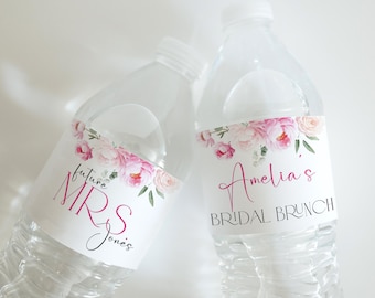 May include: Two clear plastic water bottles with labels. One label reads "future MRS Jones" in pink and black script. The other reads "Amelia's BRIDAL BRUNCH" in pink script. Both labels feature a floral design with pink and white flowers.