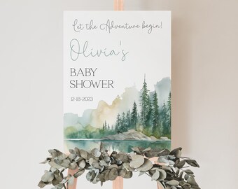 Peut inclure: Une pancarte blanche avec une illustration aquarelle d'une forêt et d'un lac. Le texte sur la pancarte indique "Let the adventure begin! Olivia's Baby Shower 12-18-2023".
