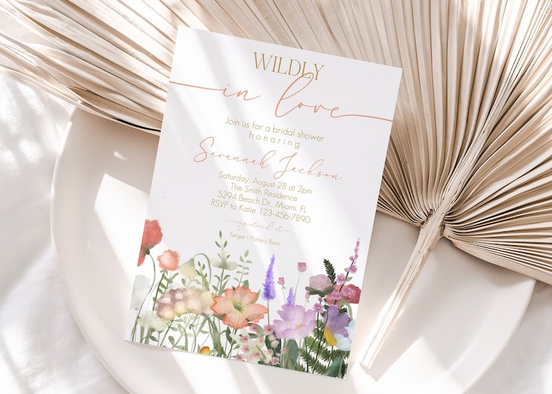 May include: A white bridal shower invitation with gold lettering that reads "WILDLY in love" and "Savannah Jackson". The invitation features a watercolor illustration of a bouquet of pink, purple, and orange flowers.