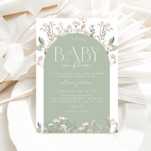 Puede incluir: Una invitación de baby shower verde y blanca con un diseño floral. El texto dice "A Sweet Baby in Bloom" e incluye detalles sobre el evento, como la fecha, la hora y el lugar.