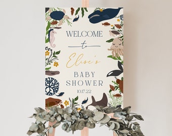 May include: A welcome sign for a baby shower with a nautical theme. The sign is decorated with sea creatures such as a whale, seahorse, jellyfish, and a turtle. The text on the sign reads "Welcome to Elise's Baby Shower 10.17.22".