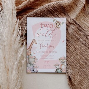 Puede incluir: Una tarjeta de invitaci&oacute;n rosa y blanca con el texto "two wild" y "Penelope's Second Birthday". La tarjeta presenta ilustraciones de animales de safari como una jirafa, un elefante y una cebra, con detalles florales.