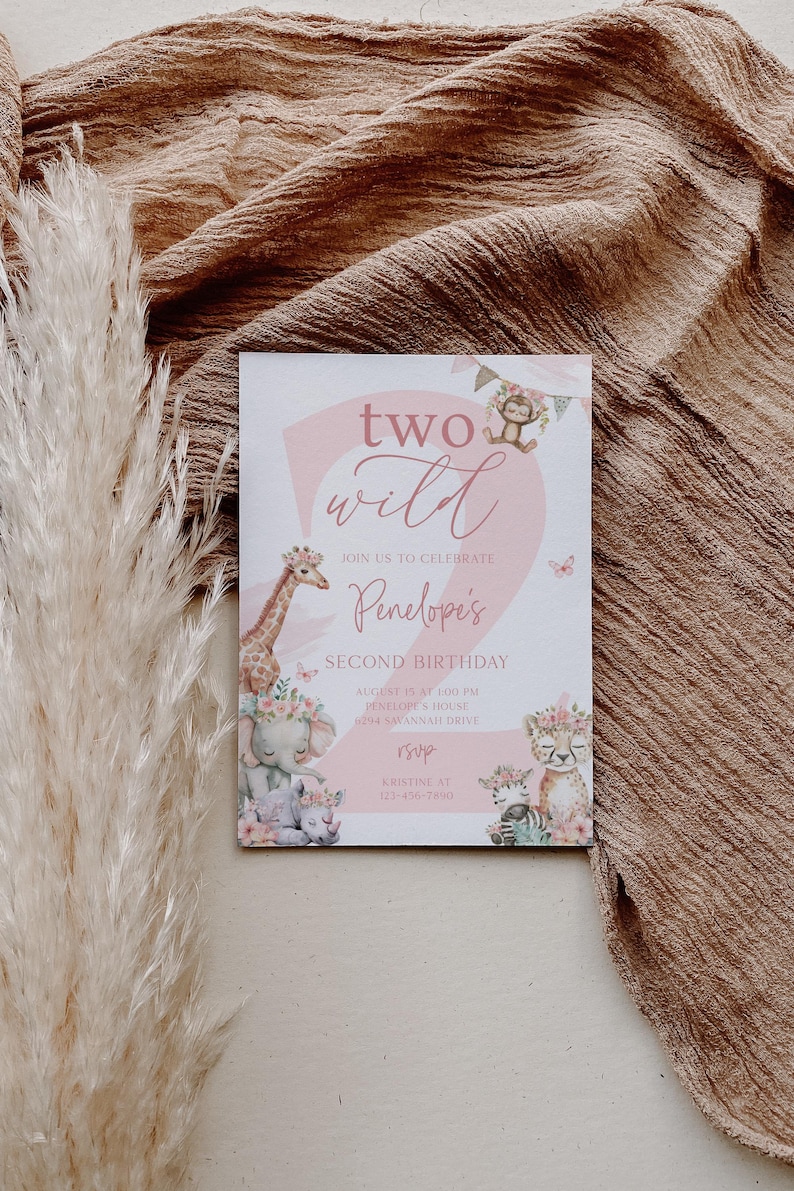 Puede incluir: Una tarjeta de invitaci&oacute;n rosa y blanca con el texto "two wild" y "Penelope's Second Birthday". La tarjeta presenta ilustraciones de animales de safari como una jirafa, un elefante y una cebra, con detalles florales.