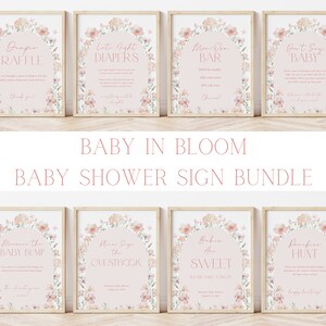 May include: A set of ten printable baby shower signs with a floral theme. The signs feature pink and white floral illustrations with text that says "Baby in Bloom", "Diaper Raffle", "Late Night Diapers", "Mom-osa Bar", "Don't Say Baby", "Guess the Baby Bump", "Please Sign the Guestbook", "Babies Are Sweet", "Pacifier Hunt", and "Happy Birthday".