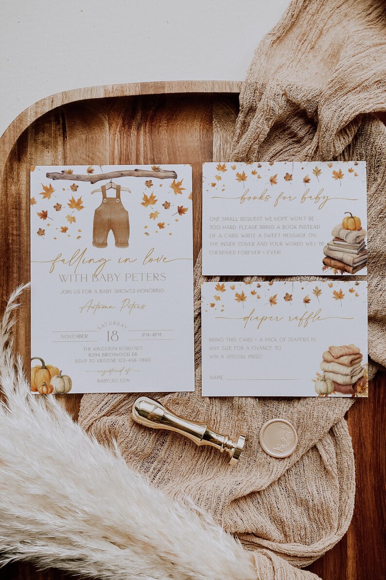 May include: Baby shower invitation set with a fall theme. The invitation features watercolor overalls and autumn leaves. Includes a book request card, diaper raffle card, and a gold wax seal.