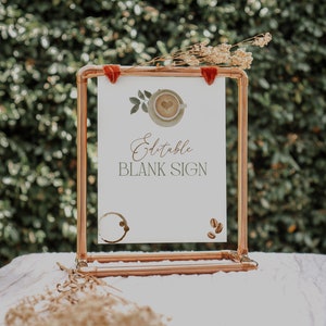 May include: A copper pipe stand with a white sign that says "Editable Blank Sign". The sign has a watercolor illustration of a coffee cup with a heart in the foam. There are coffee beans on the sign.