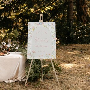 May include: A welcome sign for a baby shower with a floral design and butterflies. The sign says "Welcome to Olivia's Baby Shower, March 24, 2023".
