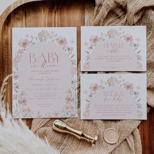 May include: A set of three baby shower cards with floral designs. The cards are white with pink floral borders and text that reads "Baby in Bloom", "Diaper Raffle", and "Books for Baby".
