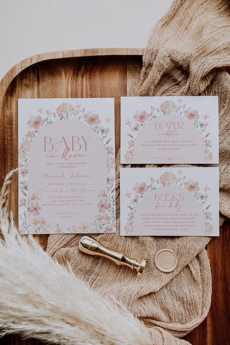 May include: A set of three baby shower cards with floral designs. The cards are white with pink floral borders and text that reads "Baby in Bloom", "Diaper Raffle", and "Books for Baby".