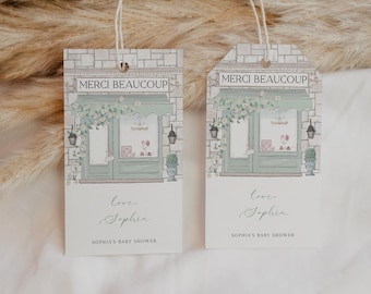 Puede incluir: Dos etiquetas de regalo blancas con una ilustración de fachada de tienda verde y el texto "Merci Beaucoup" en cada una. El texto "love, Sophia" y "Sophia's Baby Shower" está impreso en la parte inferior de cada etiqueta.