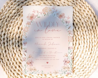 May include: A pink and white floral bridal shower invitation with the text "WILDLY in love" and the bride's name "Hannah Johnson". The invitation includes the date, time, and location of the shower, as well as the RSVP information. The invitation is decorated with a watercolor floral design.