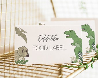 Pode incluir: Etiqueta de comida editável com tema de dinossauros. A etiqueta apresenta um T-Rex verde, um Triceratops marrom e um Pterodactyl voando.
