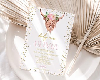 May include: A rectangular invitation card featuring a watercolor illustration of a highland cow wearing a floral crown. The text reads: holy cow OLIVIA is turning one! Join us for a celebration Saturday September 27 at 12PM Rodeo Ranch 6394 Moo Drive Houston, TX 63920 rsvp to Michelle at 123-456-7890. The border is decorated with gold confetti dots.