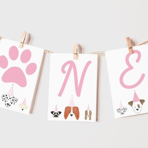 May include: Pink and white banner with the word "ONE" in pink letters. The banner has a pink paw print and images of dogs wearing party hats.