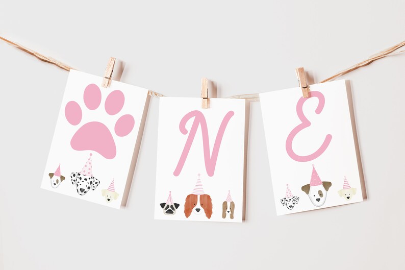 May include: Pink and white banner with the word "ONE" in pink letters. The banner has a pink paw print and images of dogs wearing party hats.