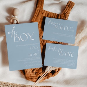 May include: Blue baby shower invitation cards with white text. The main card says "Oh Boy!" and has the names Lucy and Blake. The other cards say "Diaper Raffle" and "Books for Baby".