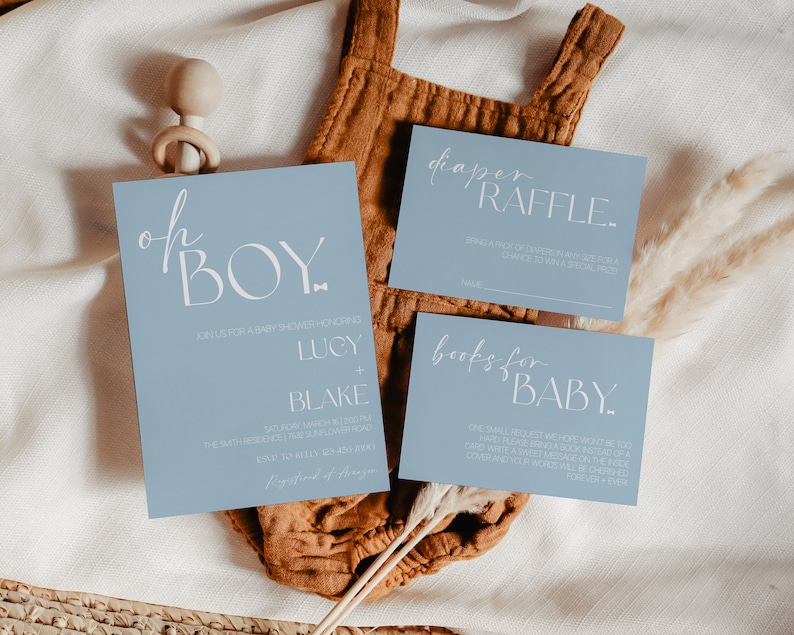May include: Blue baby shower invitation cards with white text. The main card says "Oh Boy!" and has the names Lucy and Blake. The other cards say "Diaper Raffle" and "Books for Baby".