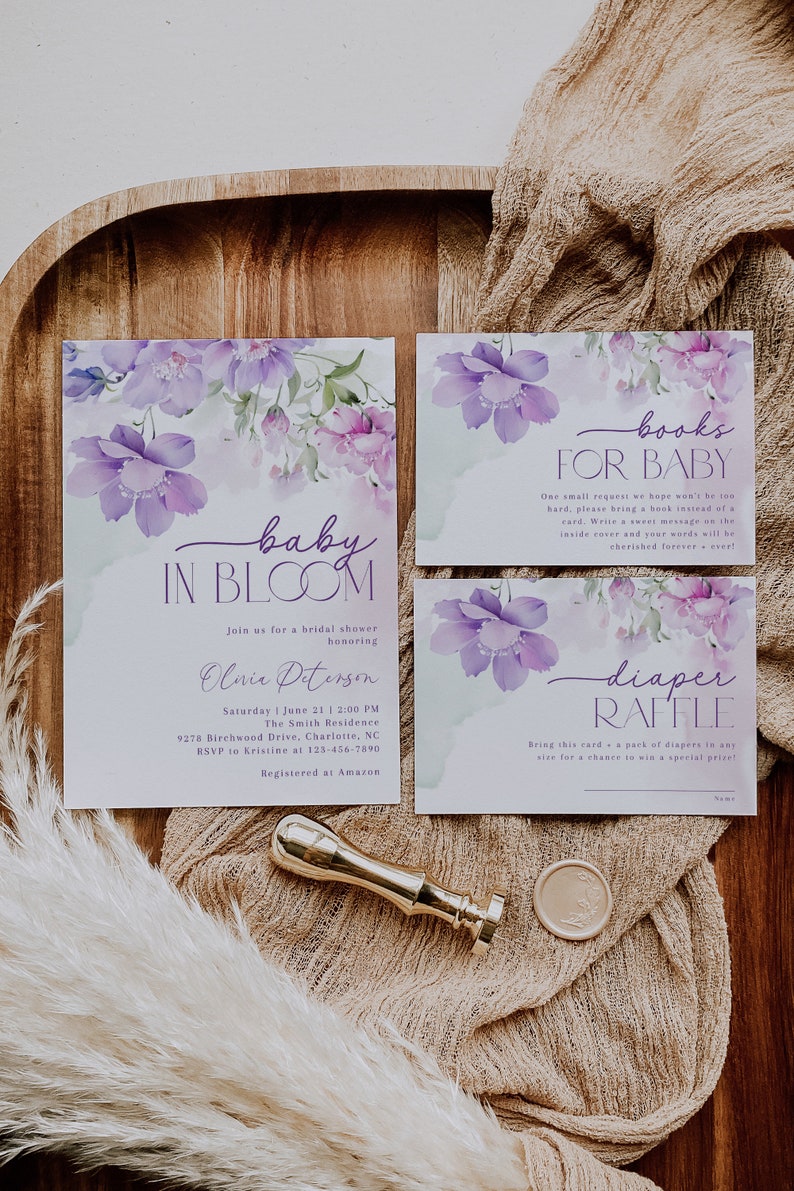May include: Purple floral baby shower invitation with the text "baby in bloom" and details for the event.  The invitation also includes a separate card for a diaper raffle and a card for a book request for the baby.