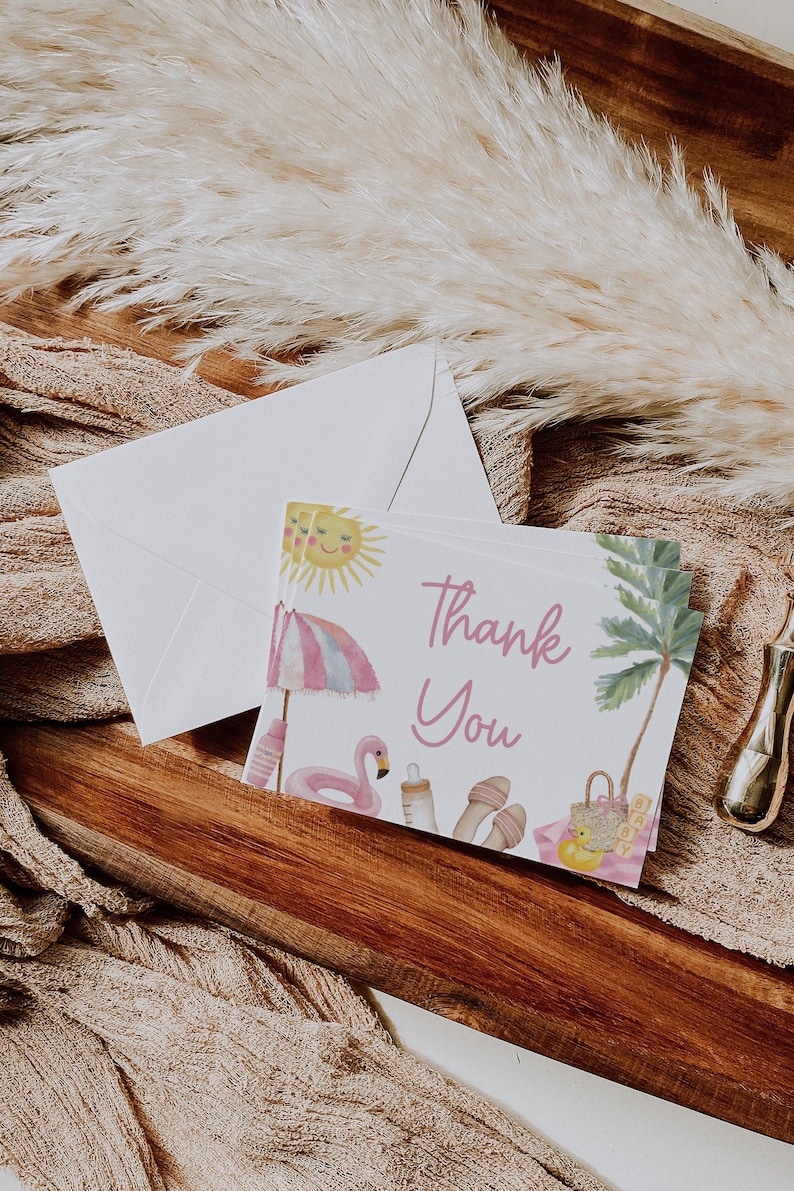 Puede incluir: Un juego de tarjetas de "Gracias" con un sobre a juego. Las tarjetas presentan una ilustraci&oacute;n de acuarela de una escena de playa con un sol, una sombrilla, un flamenco y una palmera. El texto "Gracias" est&aacute; escrito en rosa.