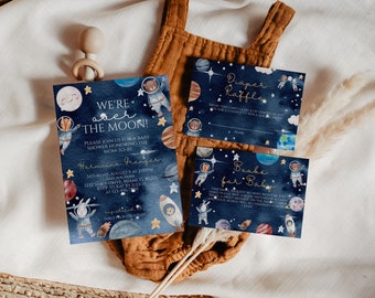 Op de afbeelding: Een set van drie babyborrelkaarten met een ruimtethema. De kaarten zijn blauw met gouden sterren en planeten. De tekst op de kaarten luidt "We're over the moon!", "Diaper Raffle" en "Books for Baby".