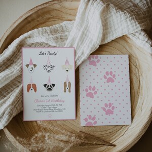 May include: A pink and white paw print patterned invitation card with the text "Let's Pawty!" and "Claire's 1st Birthday" with a list of details for the party.