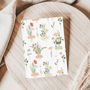 May include: A white card with a repeating pattern of small floral bouquets. Each bouquet is made up of pink, yellow, and orange flowers with green leaves. The bouquets are tied with a light brown ribbon.
