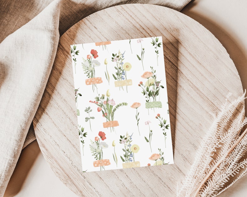May include: A white card with a repeating pattern of small floral bouquets. Each bouquet is made up of pink, yellow, and orange flowers with green leaves. The bouquets are tied with a light brown ribbon.