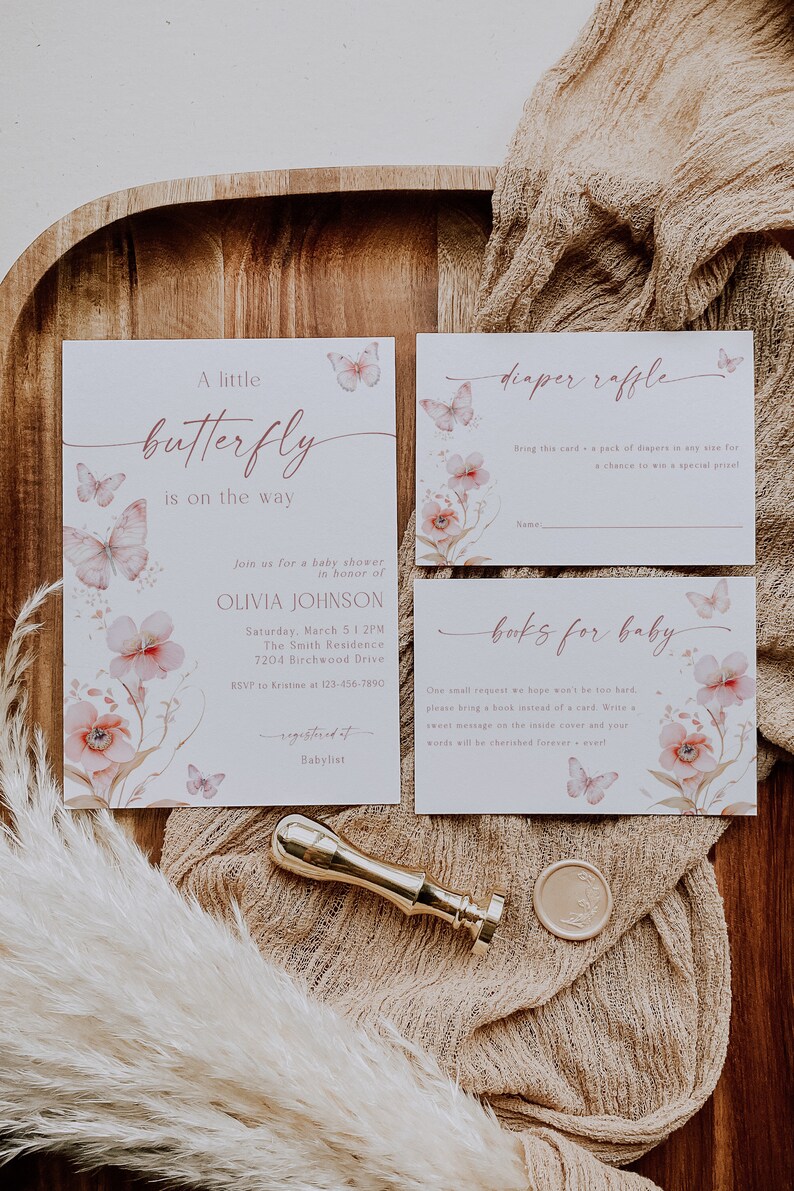 May include: A baby shower invitation with a pink and white floral design and butterflies. The invitation says "A little butterfly is on the way" and includes the name Olivia Johnson. There are also cards for a diaper raffle and a book request for the baby.