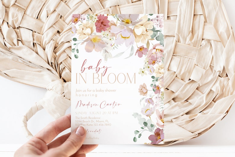 May include: A baby shower invitation featuring a floral design in shades of pink, white, and green. The text reads "baby in bloom" and includes the name "Madison Carter".