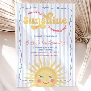 May include: A birthday invitation with a whimsical design. The text "Our Little Sunshine is Turning One!" is in yellow and pink. The invitation includes details for Salem's 1st birthday, featuring a smiling sun illustration and blue striped background.