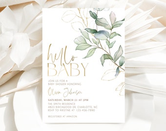 May include: A white baby shower invitation with gold lettering that says "hello baby". The invitation features a watercolor illustration of eucalyptus leaves and branches with gold accents. The text includes the date, time, location, and RSVP information.