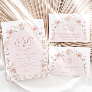 May include: Baby shower invitation featuring a floral design. The invitation reads "Baby in Bloom" and includes the name "Hannah Johnson". There are also two cards for guests to bring books or nappies for the baby.